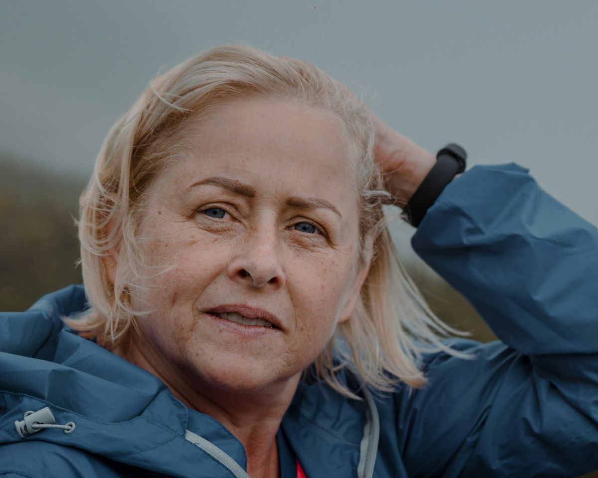 Woman outside on a windy and gray day in a windbreaker.